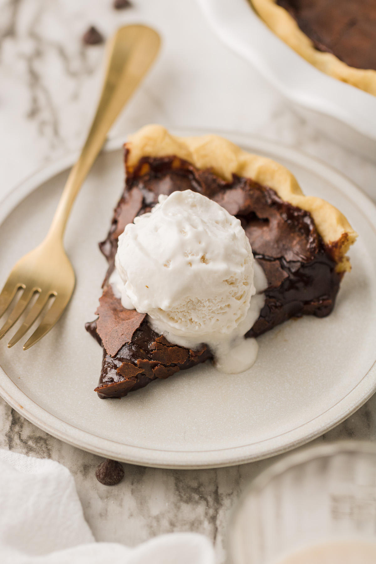 Vegan chocolate chess pie on plate with fork and scoop of ice cream