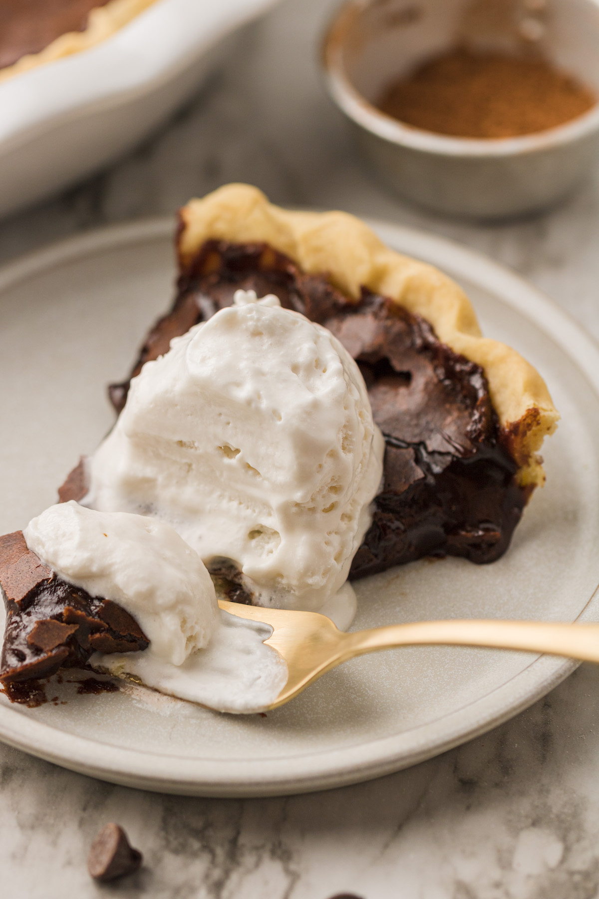 Chocolate chess pie on plate with fork, topped with vanilla ice cream