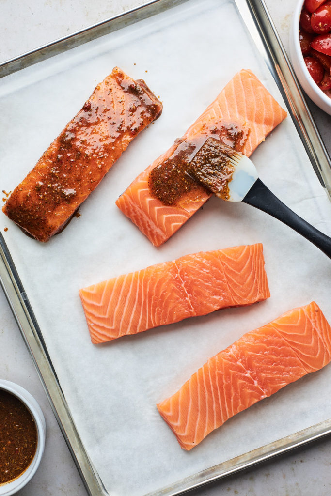 Jerk marinade being spread on salmon filets