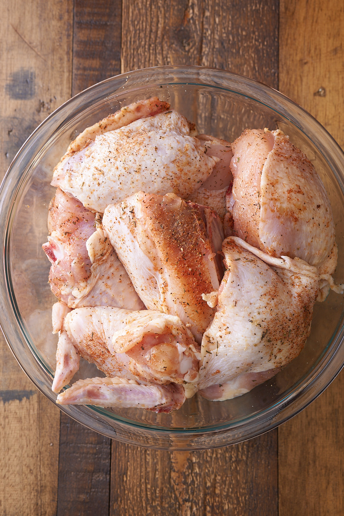 chicken covered in seasonings in glass bowl