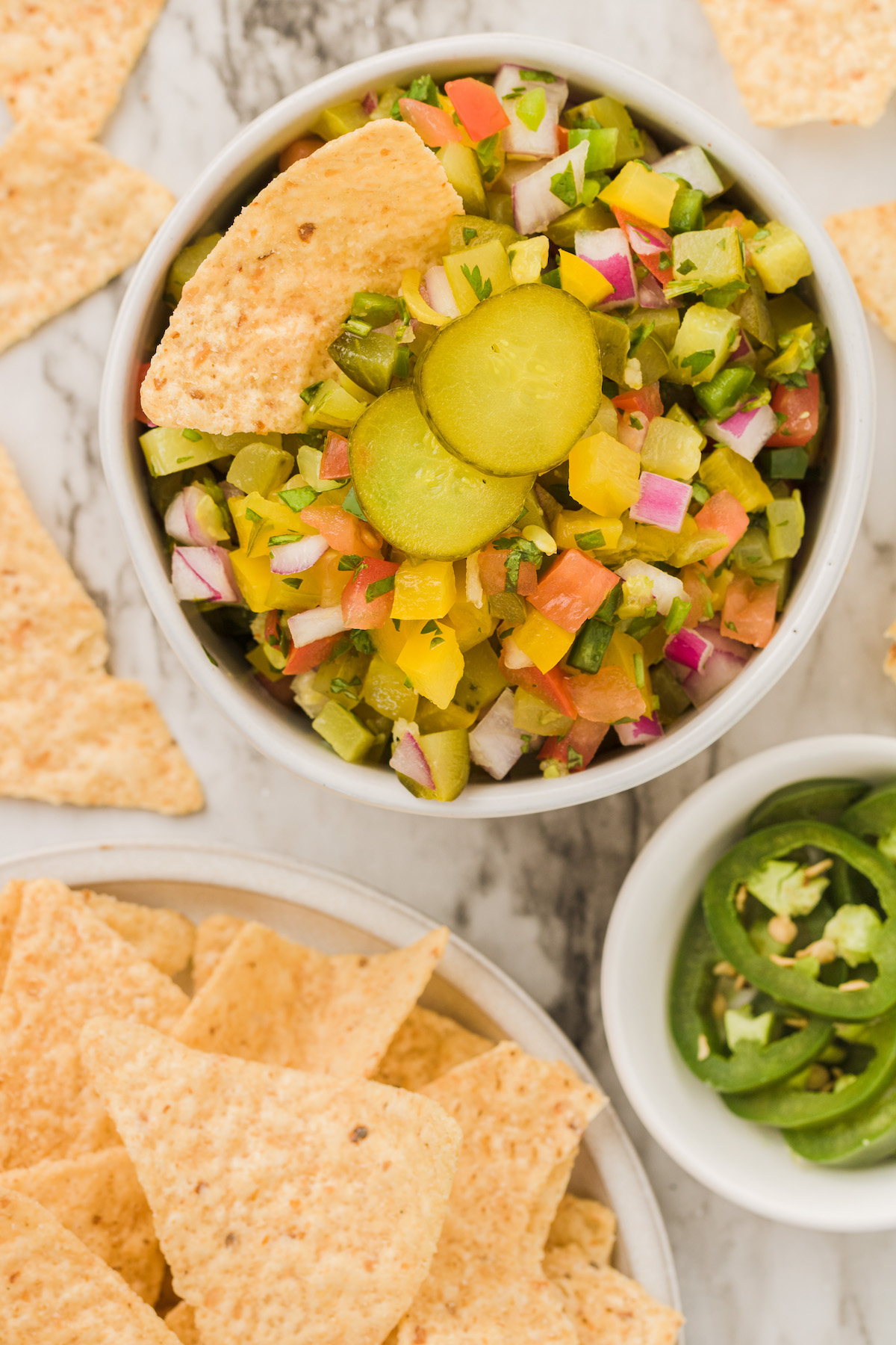 Overhead view of pickle de gallo in bowl with tortilla chip and pickle slices