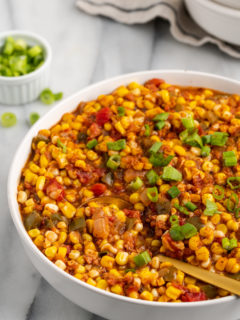 Large bowl of vegan corn maque choux with serving spoon