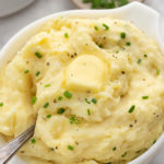 Buttermilk mashed potatoes in a large white bowl with melted butter