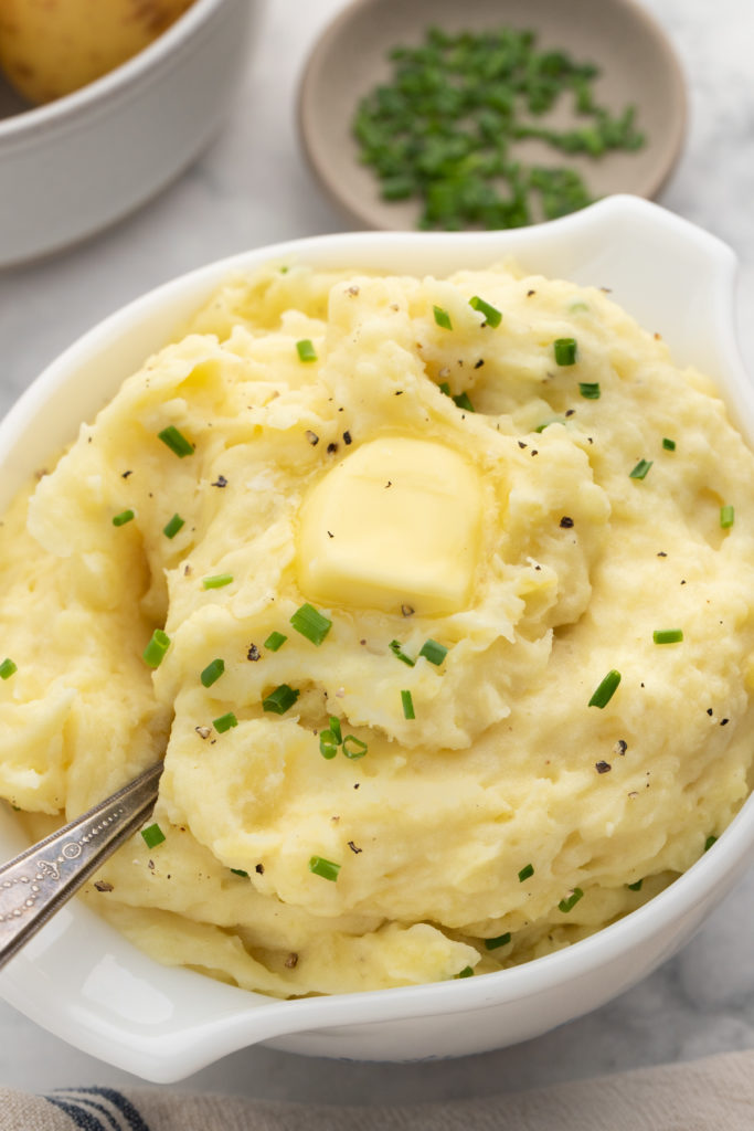 Buttermilk mashed potatoes in a large white bowl with melted butter