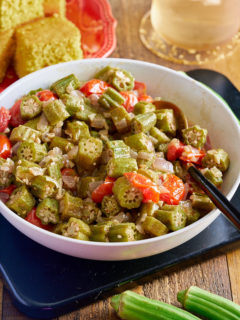 stewed okra and tomatoes in white bowl with cornbread in background