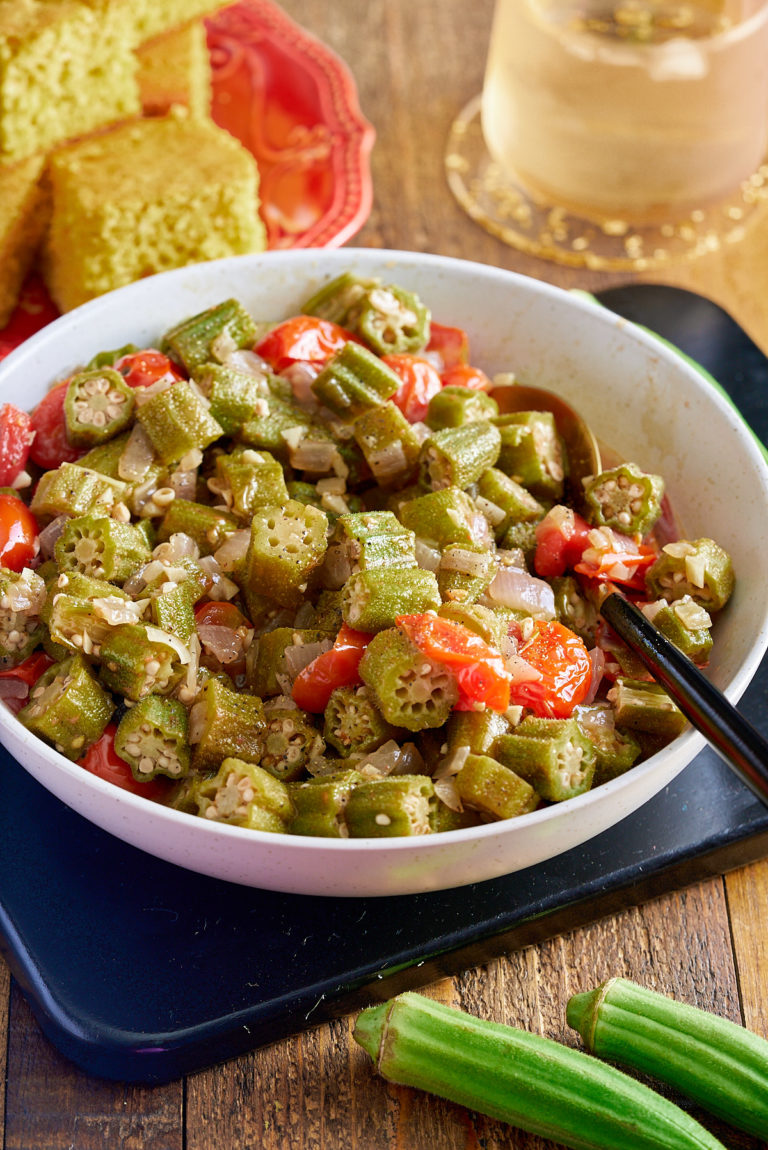 stewed okra and tomatoes in white bowl with cornbread in background