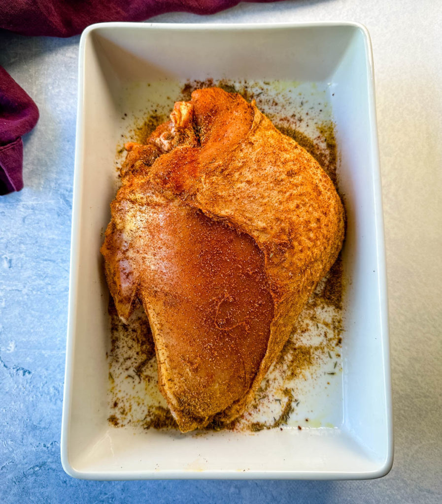 raw, seasoned bone in turkey breast in a pan