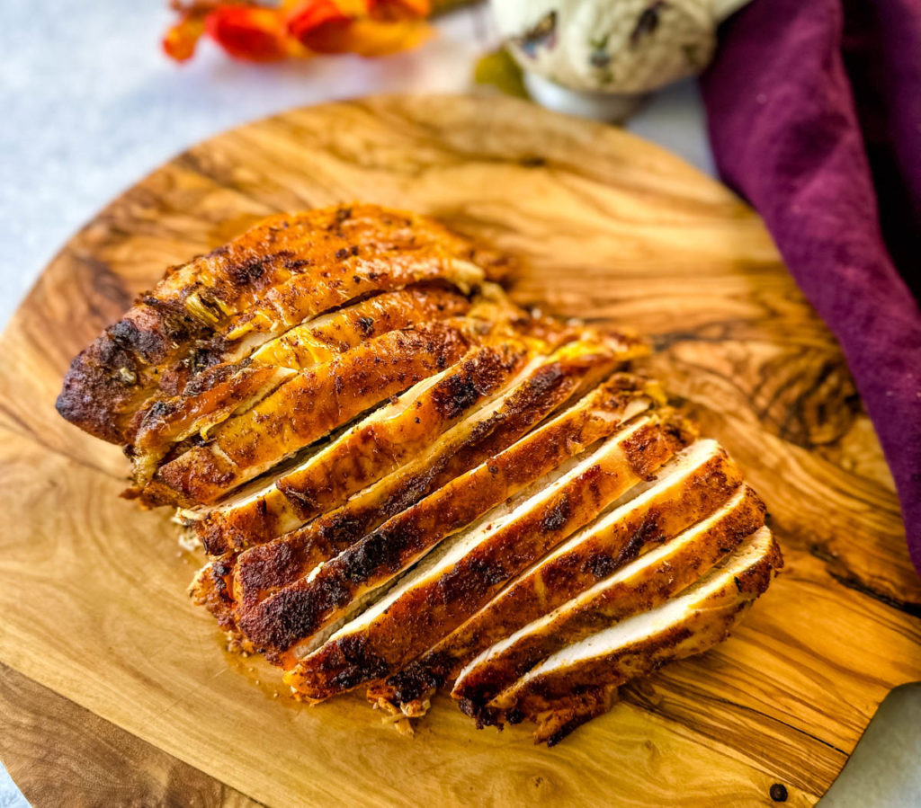 slices of cooked, baked, roasted turkey breast on a wooden cutting board