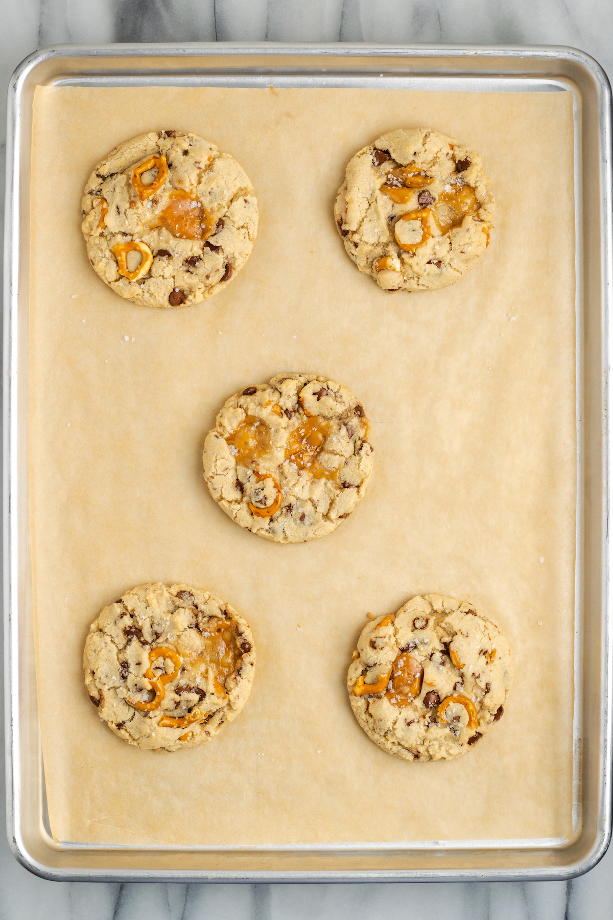 Overhead view of 5 kitchen sink cookies on parchment-lined baking sheet