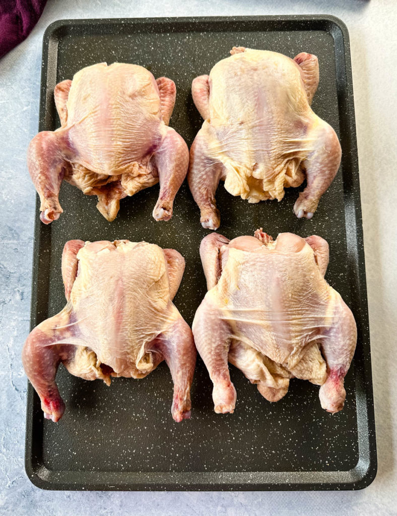raw Cornish hens on a sheet pan