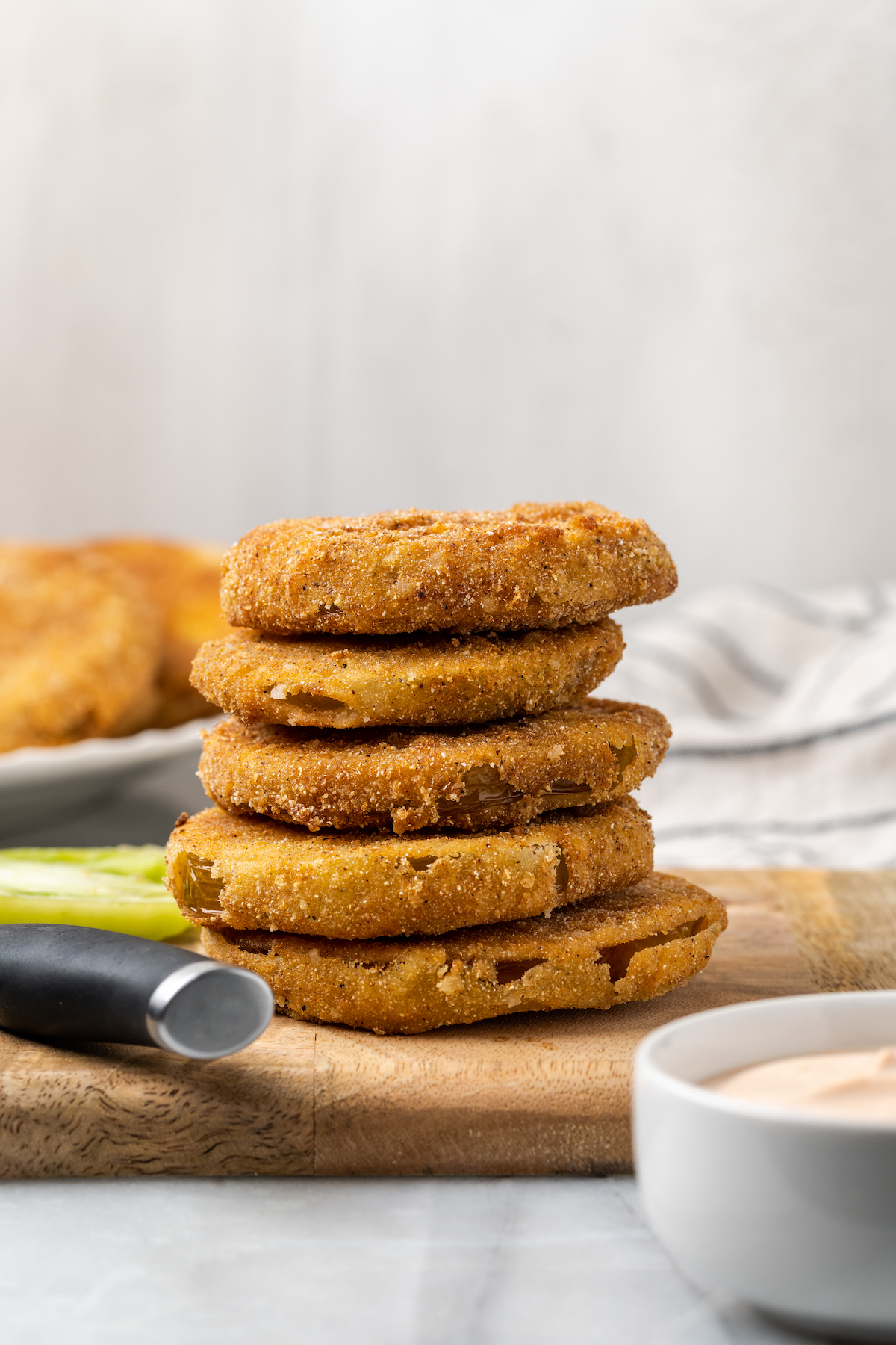 Stack of 5 fried green tomatoes on wooden cutting board