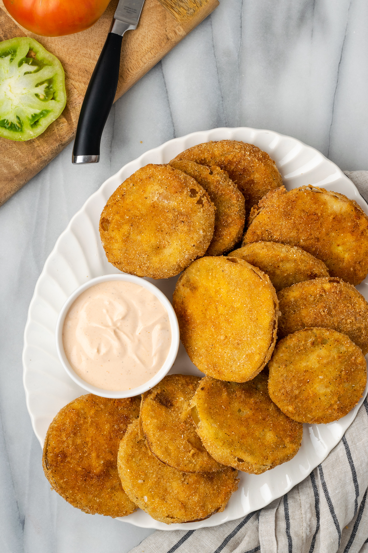 Overhead view of fried green tomatoes on platter with bowl of comeback sauce