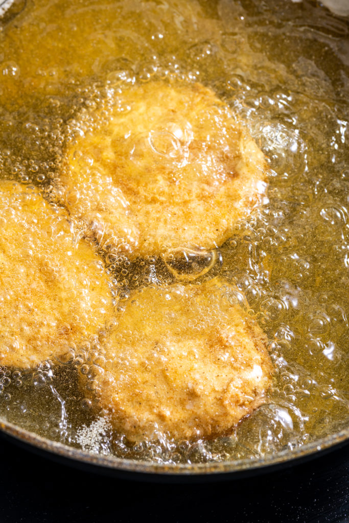 Fried green tomatoes being cooked in pot of oil