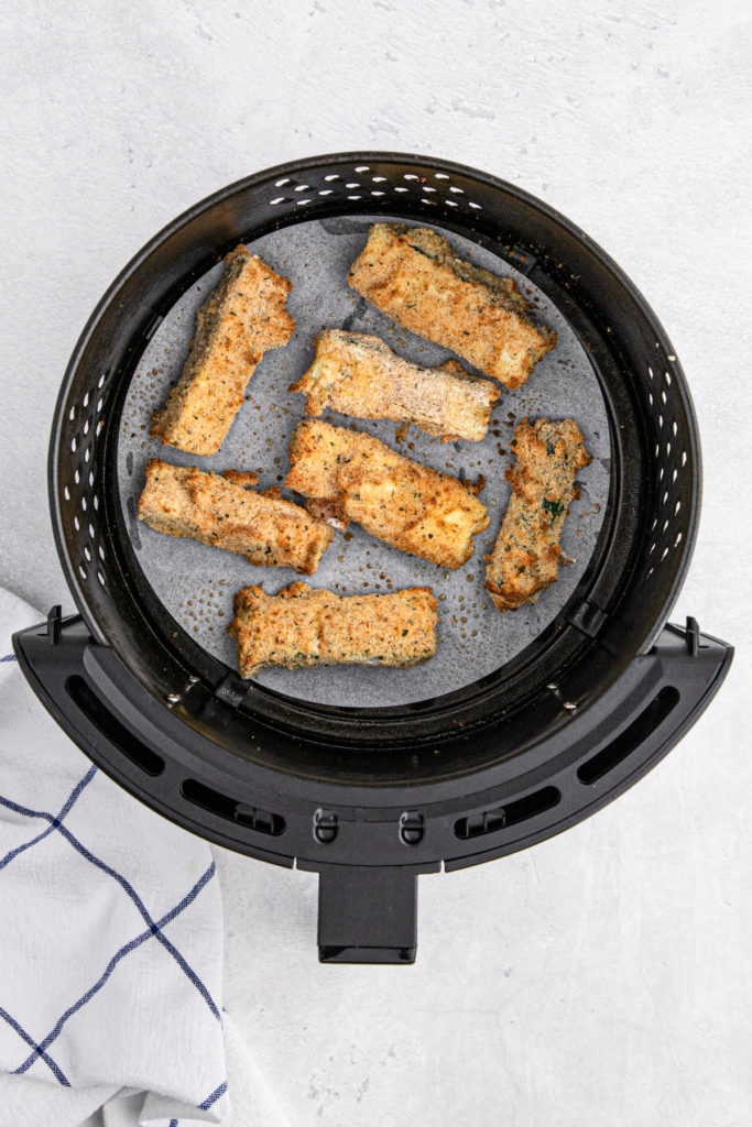 Dredged zucchini on parchment in an air fryer