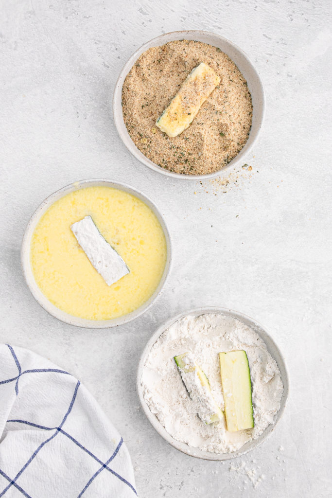 Spears of zucchini in bread crumbs, then in eggs and flour for dredging