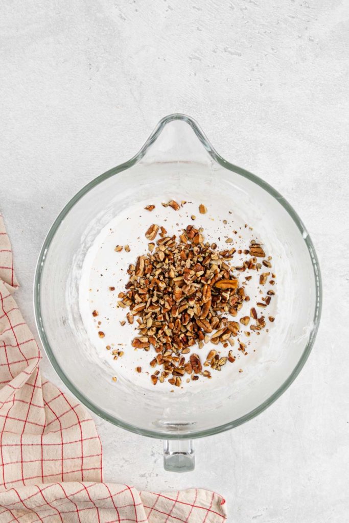 Chopped pecans in the middle of meringue mixture in mixer