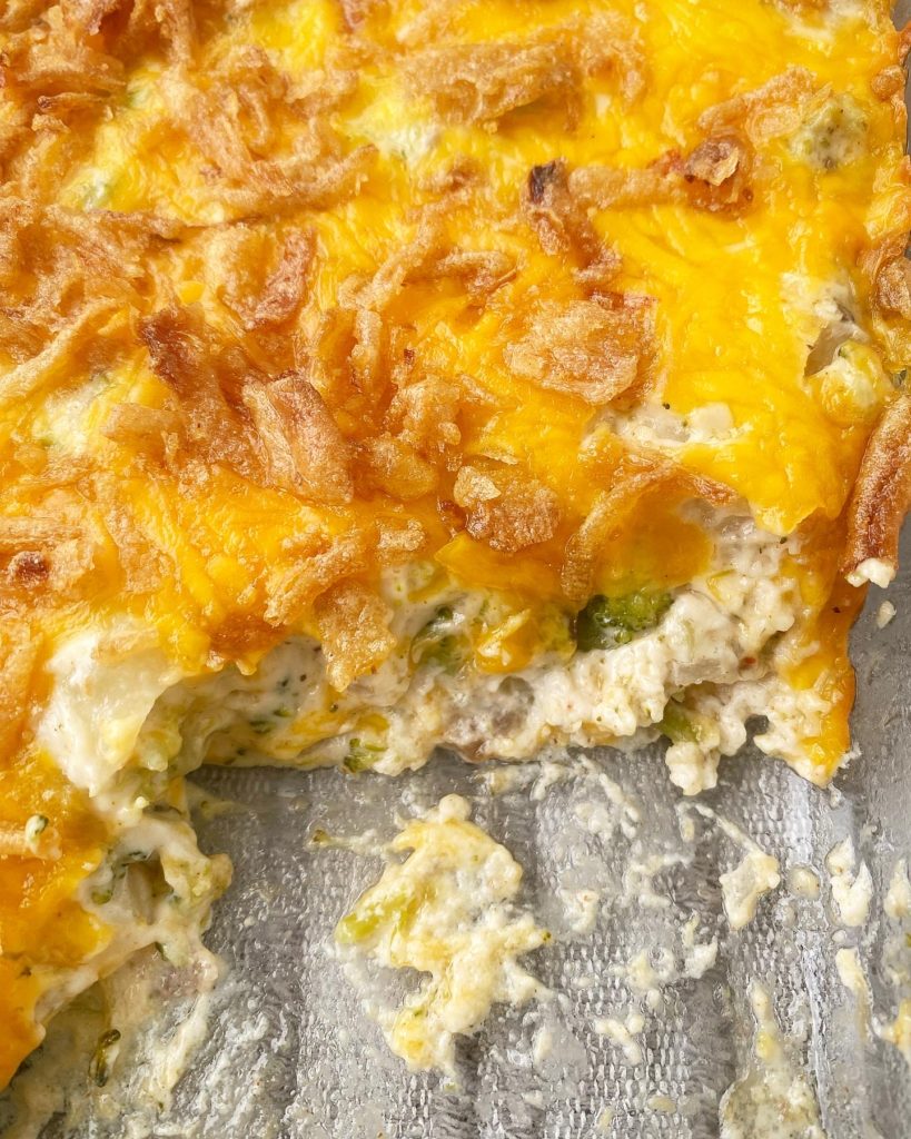 close up shot of broccoli cheese casserole in a baking dish with a scoop missing