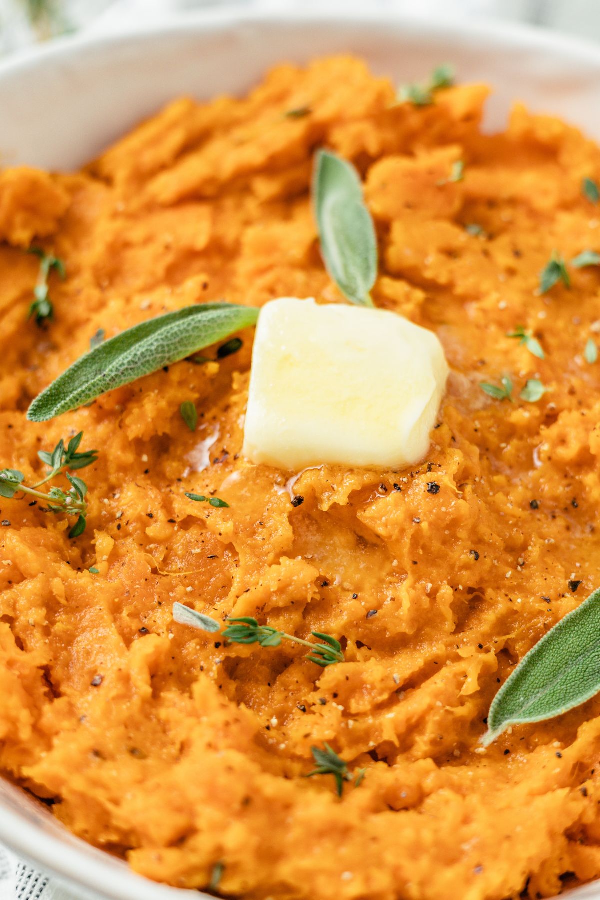 close-up shot of Savory Mashed sweet Potatoes topped with butter and some herbs