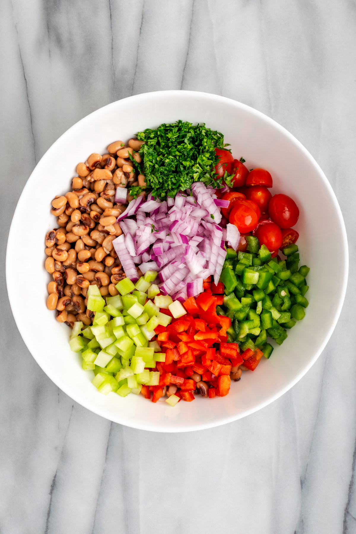 Overhead view of salad ingredients in large white mixing bowl