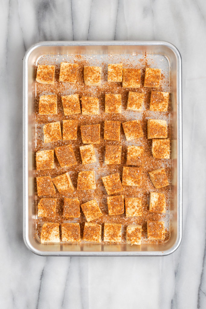 Overhead view of seasoned tofu on sheet pan