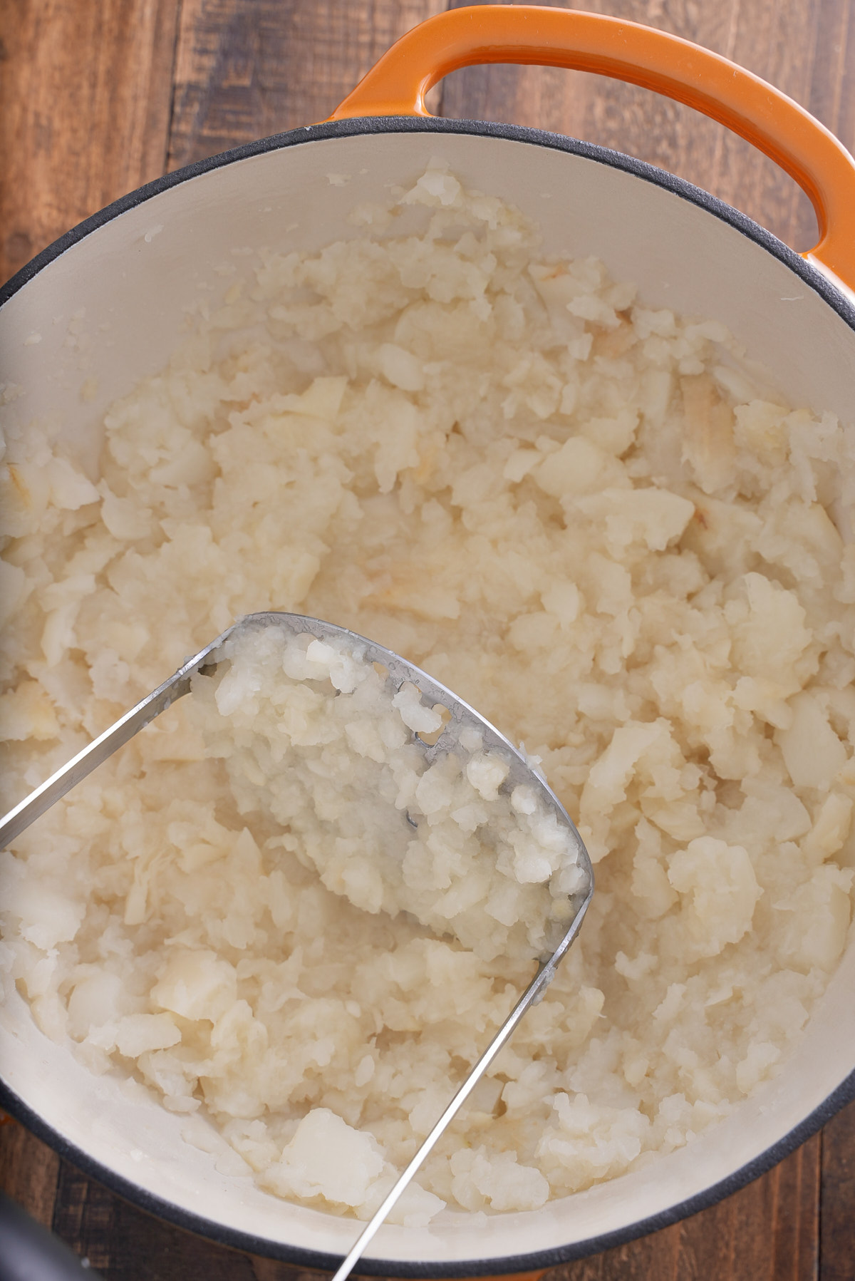 turnips mashed in pot with potato masher inside of the pot