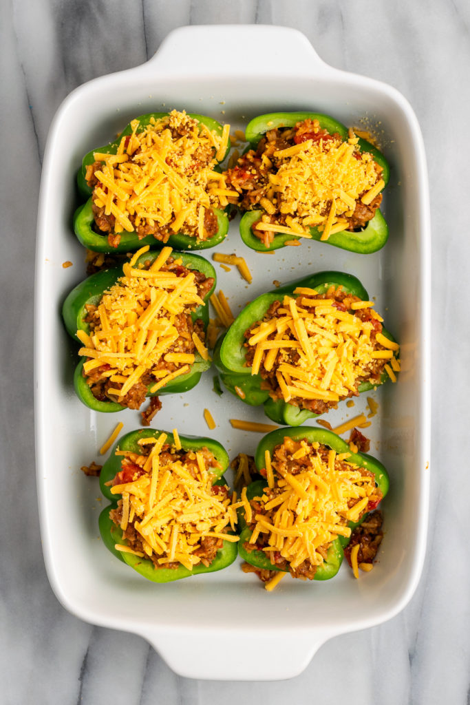 Overhead view of stuffed green peppers in baking dish before baking