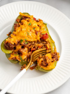 Overhead view of fork cutting into vegan stuffed pepper on plate