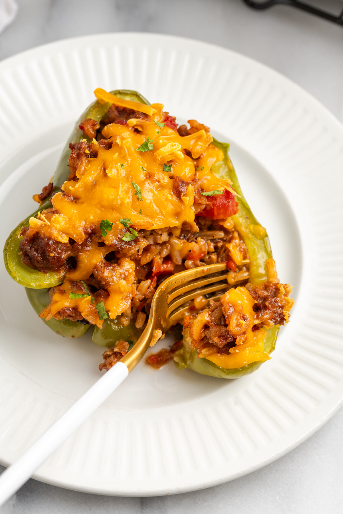 Overhead view of fork cutting into vegan stuffed pepper on plate