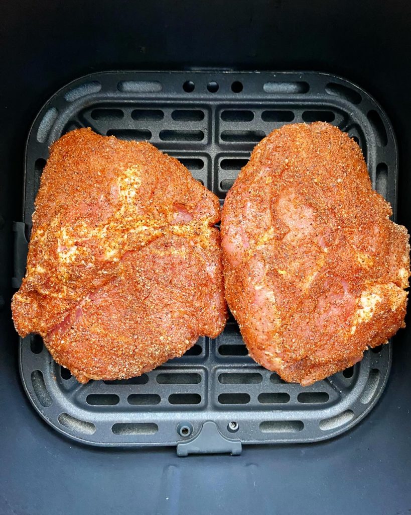 overhead shot of uncooked air fried pork chop in a black air fryer