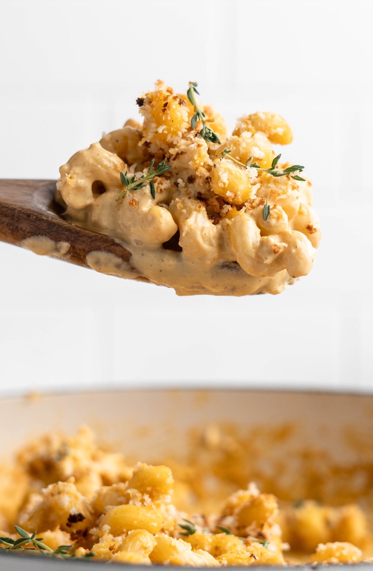 Wooden spoon lifting vegan mac and cheese from skillet
