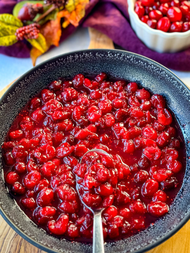homemade cranberry sauce in a black bowl with a spoon