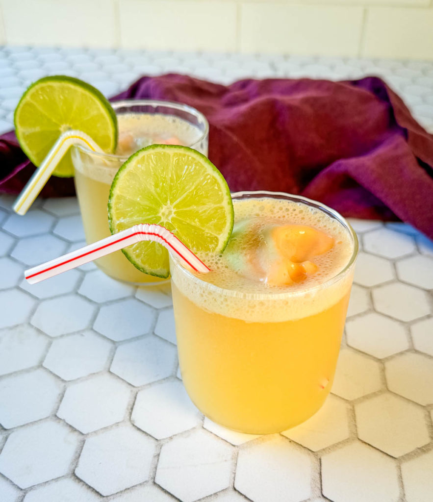 sherbet punch in a glass cup with a straw garnished with lime