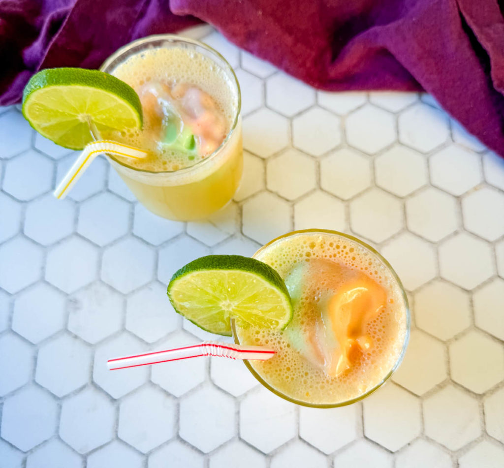sherbet punch in a glass cup with a straw garnished with lime