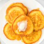Cornbread pancakes on a white plate with butter on top