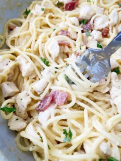 close up shot of cooked chicken carbonara in with a silver spoon