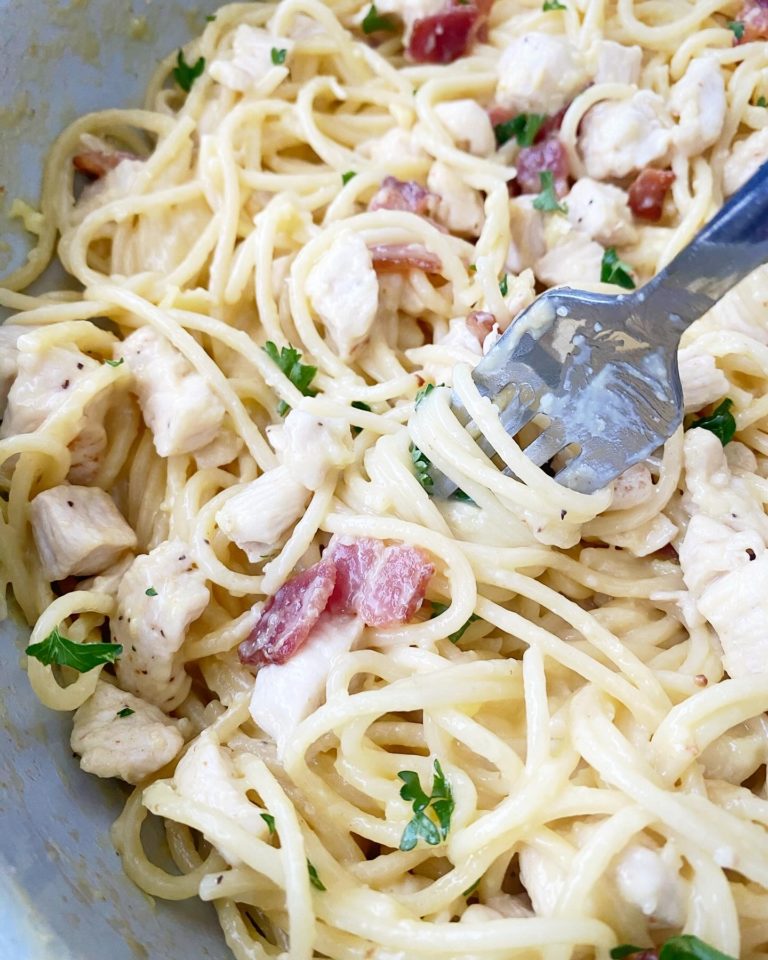 close up shot of cooked chicken carbonara in with a silver spoon