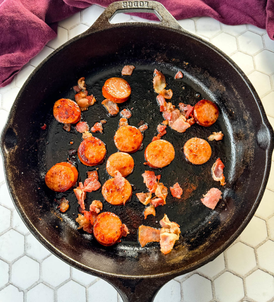 cooked sausage and bacon in a cast iron skillet