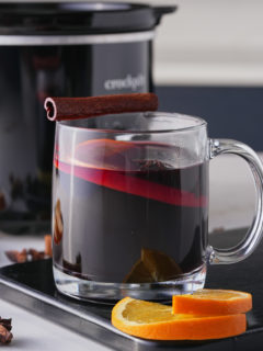 mulled wine in a glass mug in front of crockpot