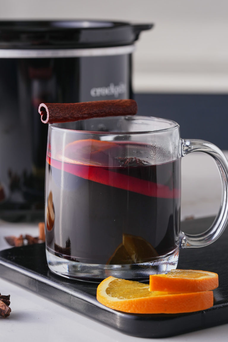 mulled wine in a glass mug in front of crockpot