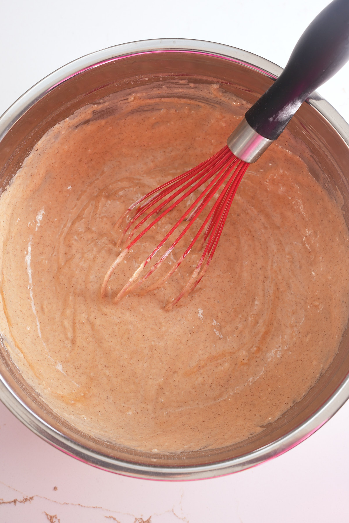 sweet potato waffle batter in bowl with whisk sticking out