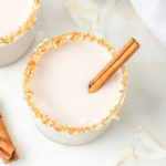 Overhead view of vegan coquito in glass with coconut rim and cinnamon stick