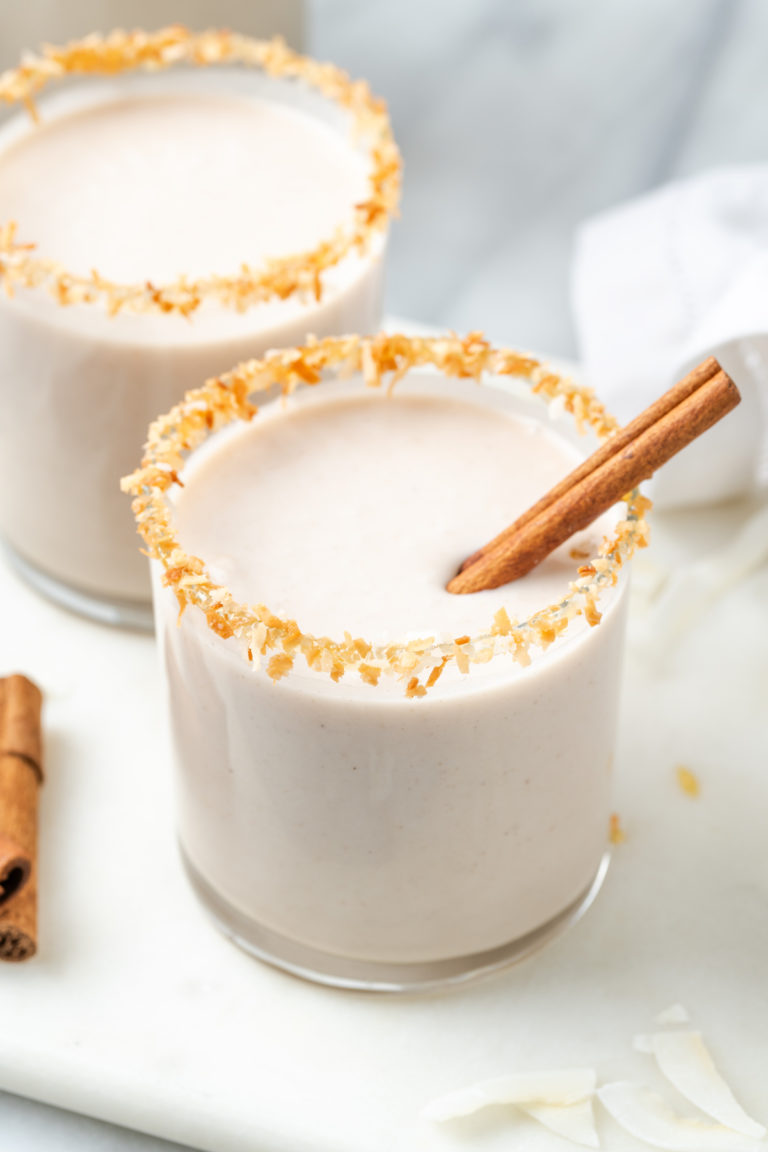 Two glasses of vegan coquito with toasted coconut rims