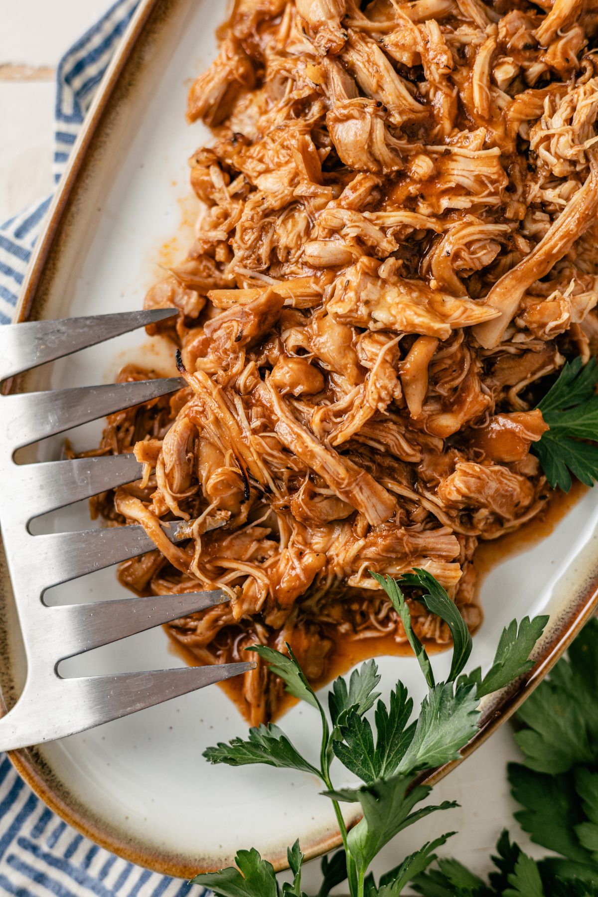 A large plate overflowing with succulent, pulled BBQ chicken, glistening in barbecue sauce, ready to be served.