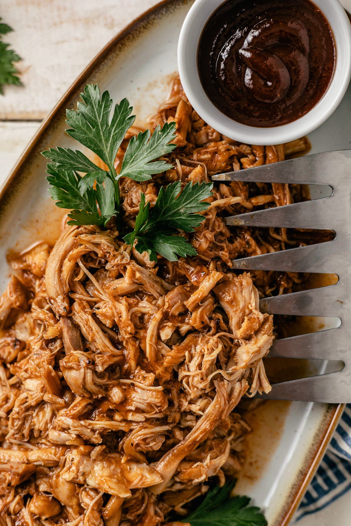 A delicious serving of juicy, pulled BBQ chicken on a large plate, with tender strands glazed in a rich, smoky barbecue sauce.