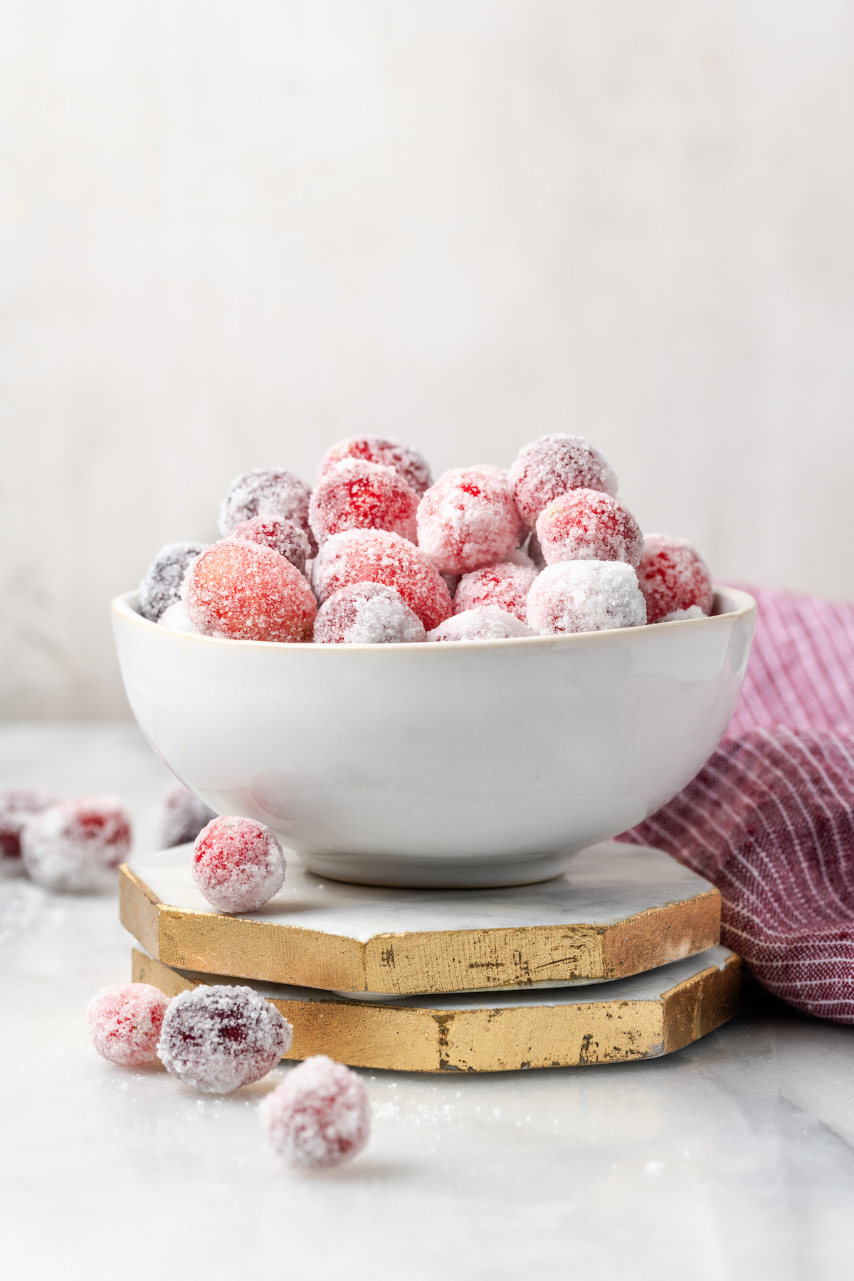 Bowl of homemade sugared cranberries on two stacked marble coasters