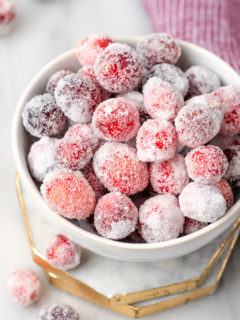Bowl of sugared cranberries set on two marble coasters