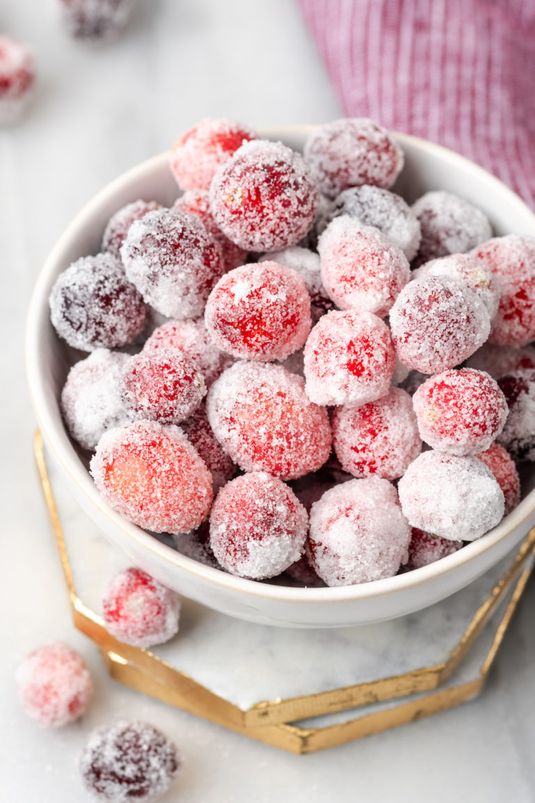 Bowl of sugared cranberries set on two marble coasters