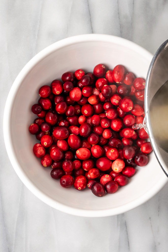 Pouring syrup over bowl of cranberries