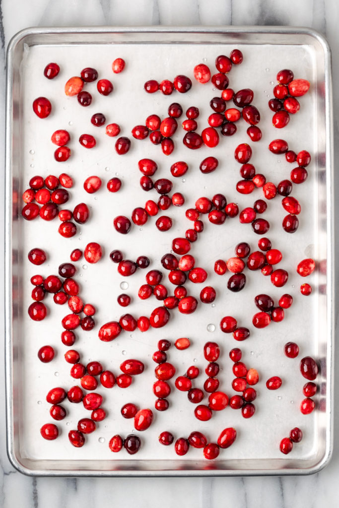 Overhead view of syrup-coated cranberries on baking sheet