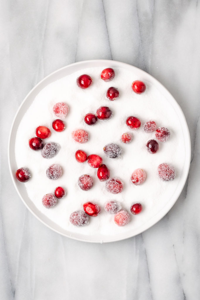 Overhead view of sugared cranberries in plate of sugar